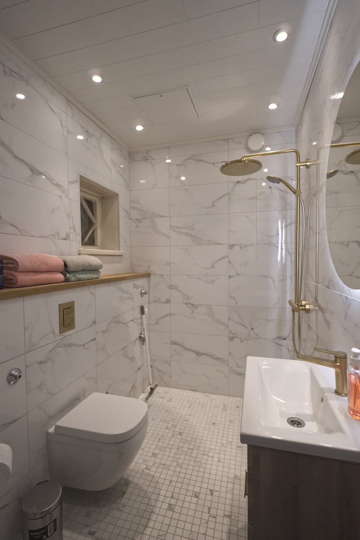 Marble bathroom with brass Grohe rain shower and round mirror
